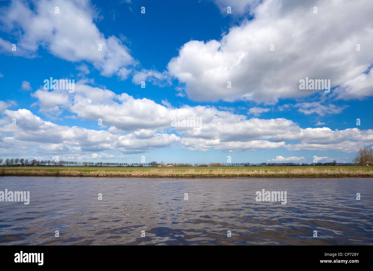 Lignes de terre, eau et ciel bleu avec des nuages gonflés bleu Banque D'Images