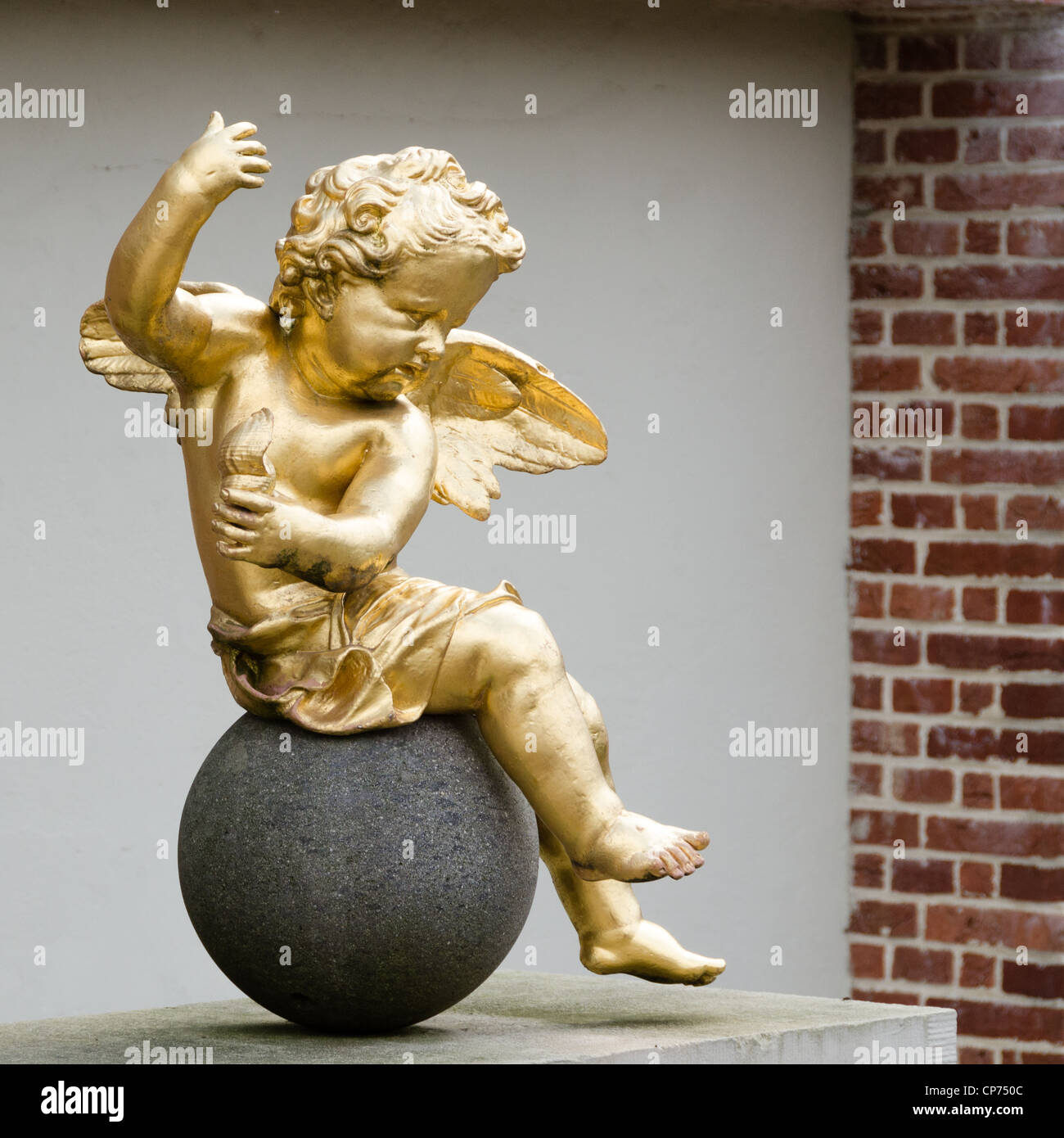 Un golden putto assis sur une pierre ronde Banque D'Images