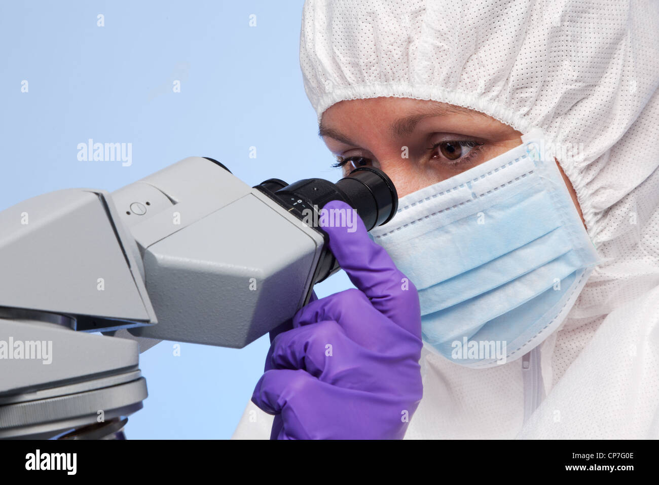 Photo d'un biochimiste à la recherche à l'aide d'un microscope de laboratoire d'optique à un spécimen sur une diapositive. Banque D'Images