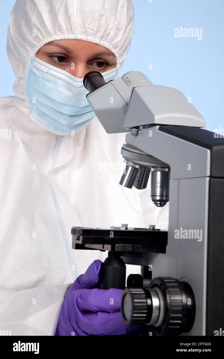 Photo d'un biochimiste à la recherche à l'aide d'un microscope de laboratoire d'optique à un spécimen sur une diapositive. Banque D'Images