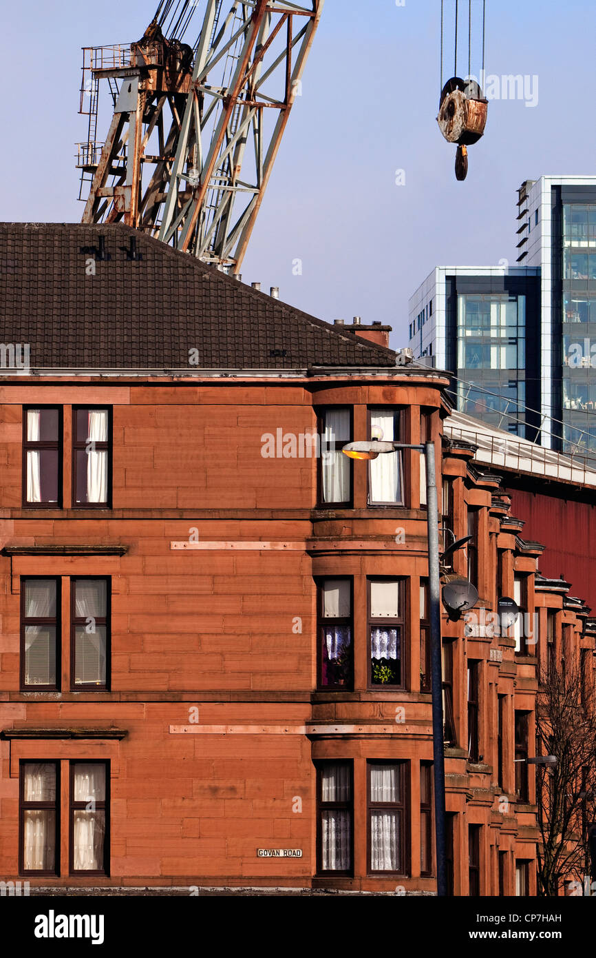 Immeuble en grès de Glasgow avec une grue à flèche relevable du chantier naval et un bâtiment de bureau à distance. Banque D'Images