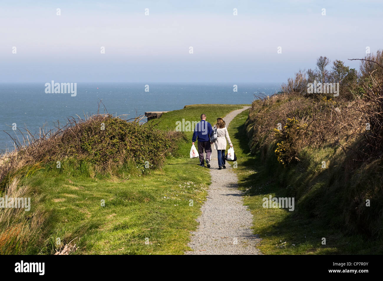 Jeune couple en train de marcher le long des sentiers côtiers irlandais à Rosslare Harbour, dans le comté de Wexford. Banque D'Images