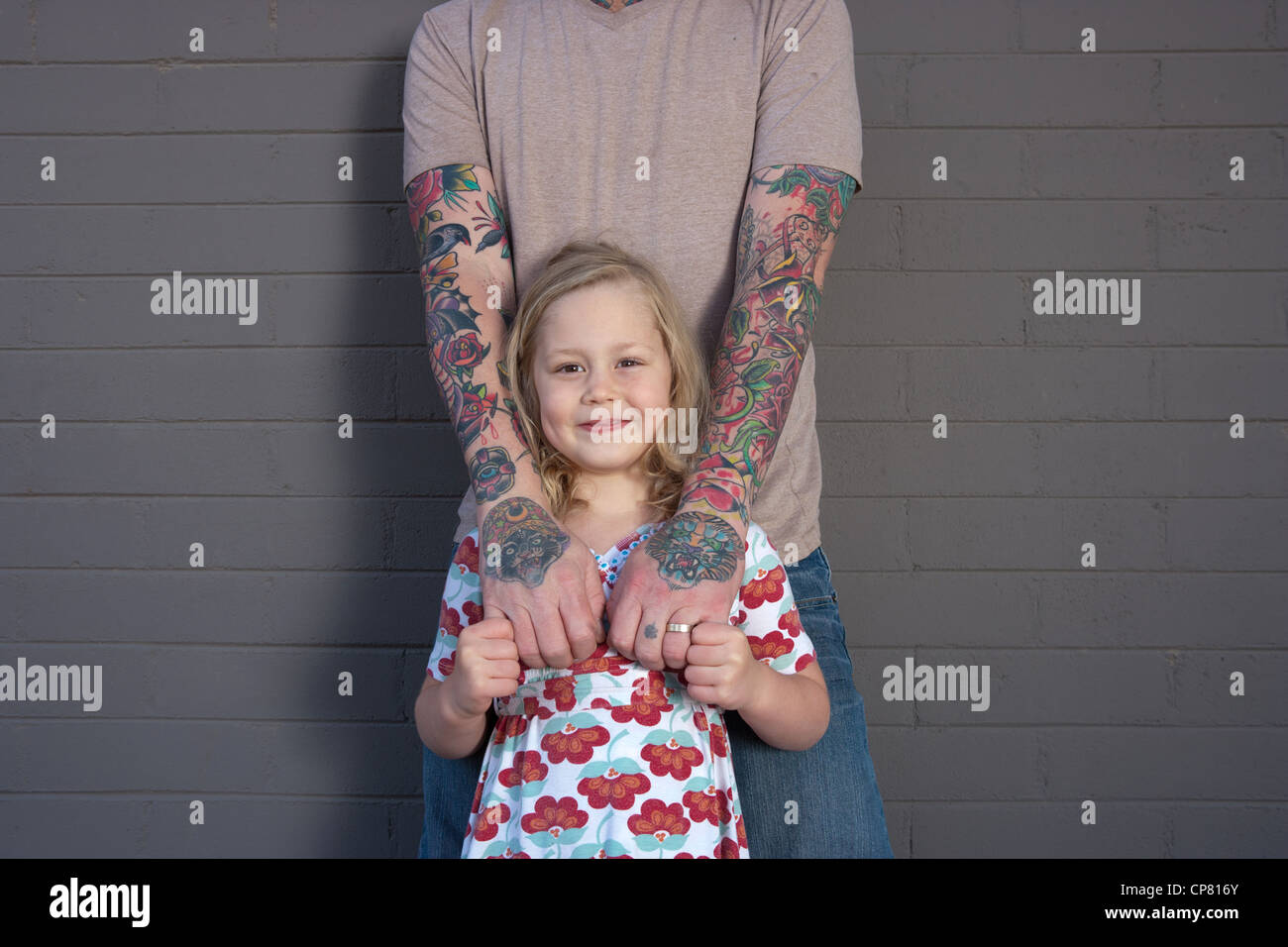 Portrait du père avec tatouage au bras et mains, debout avec sa fille âgée de cinq ans. Banque D'Images