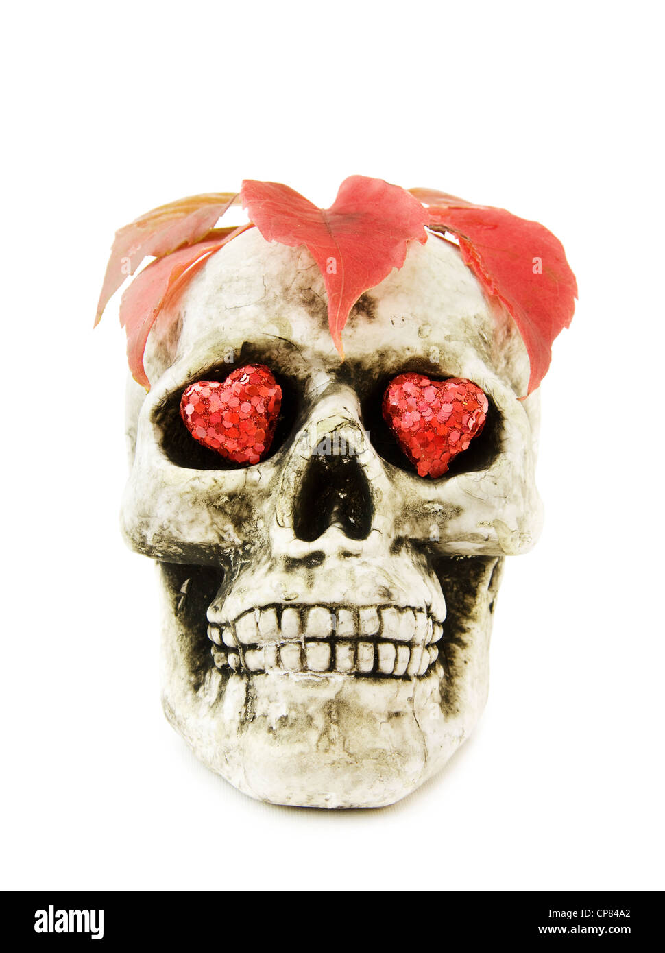 Célébrer Halloween effrayant avec crâne humain décoré avec des coeurs rouges et des feuilles mortes. Isolé sur fond blanc. Banque D'Images