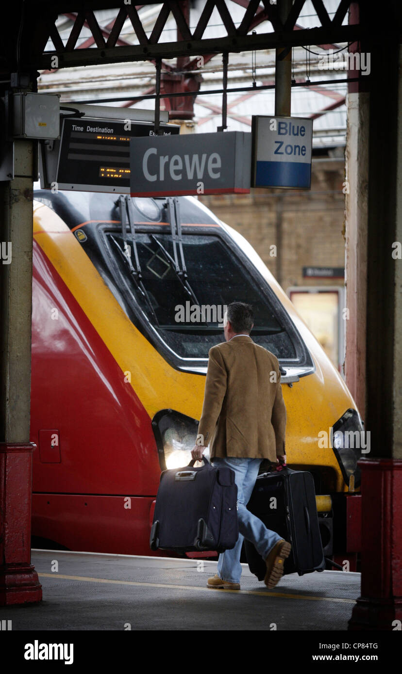 La gare de Crewe un passager marcher le long de la plate-forme passé un train Voyager vierge Banque D'Images