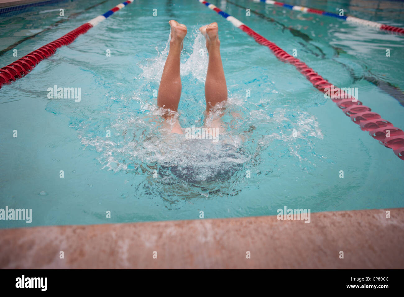 Garçon debout à l'envers dans une piscine, les jambes vers le haut hors de l'eau. Banque D'Images