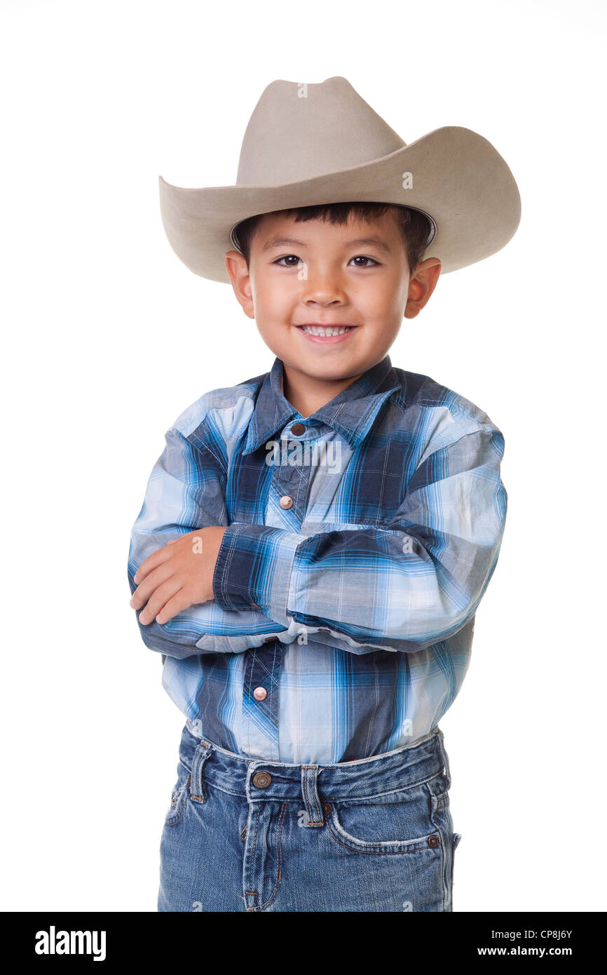 Un jeune garçon, en vêtements cowboy croise les bras et affiche un grand sourire. Banque D'Images
