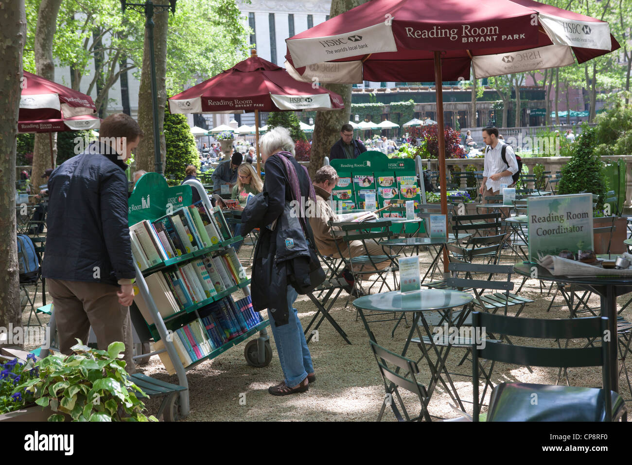 Les gens parcourir la sélection de livres sur les chariots à la Bryant Park salle de lecture, une bibliothèque de plein air dans la ville de New York. Banque D'Images