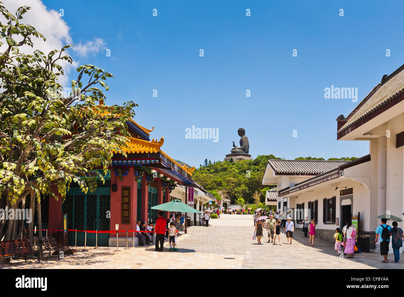 Les visiteurs dans la rue principale de Ngong Ping sur l'île de Lantau, Hong Kong, dominé par le Tian Tan Buddha statue. Banque D'Images