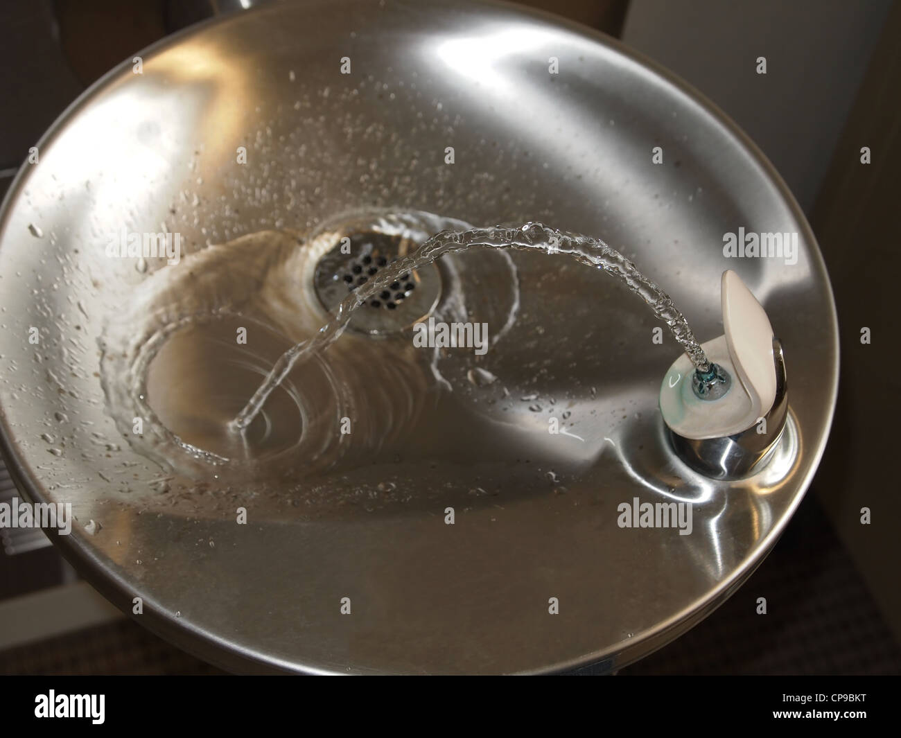 Un flux d'eau propre, eau claire dans une fontaine d'eau potable rend un arc de la tuyère dans le drain. Banque D'Images