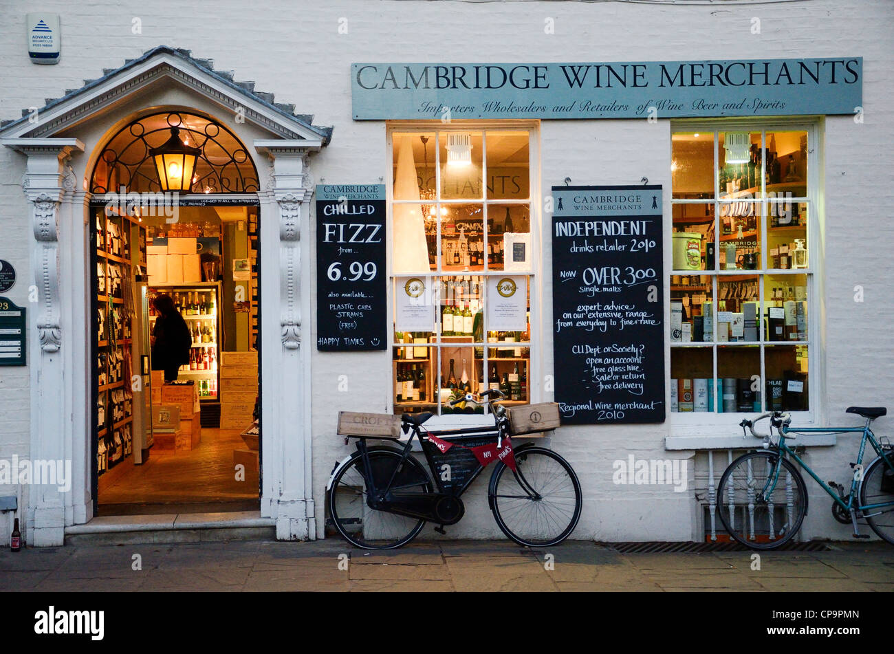 En dehors d'un magasin de vins de la rue Cambridge avec éclairage sur l'intérieur et à pousser les vélos contre le mur Banque D'Images