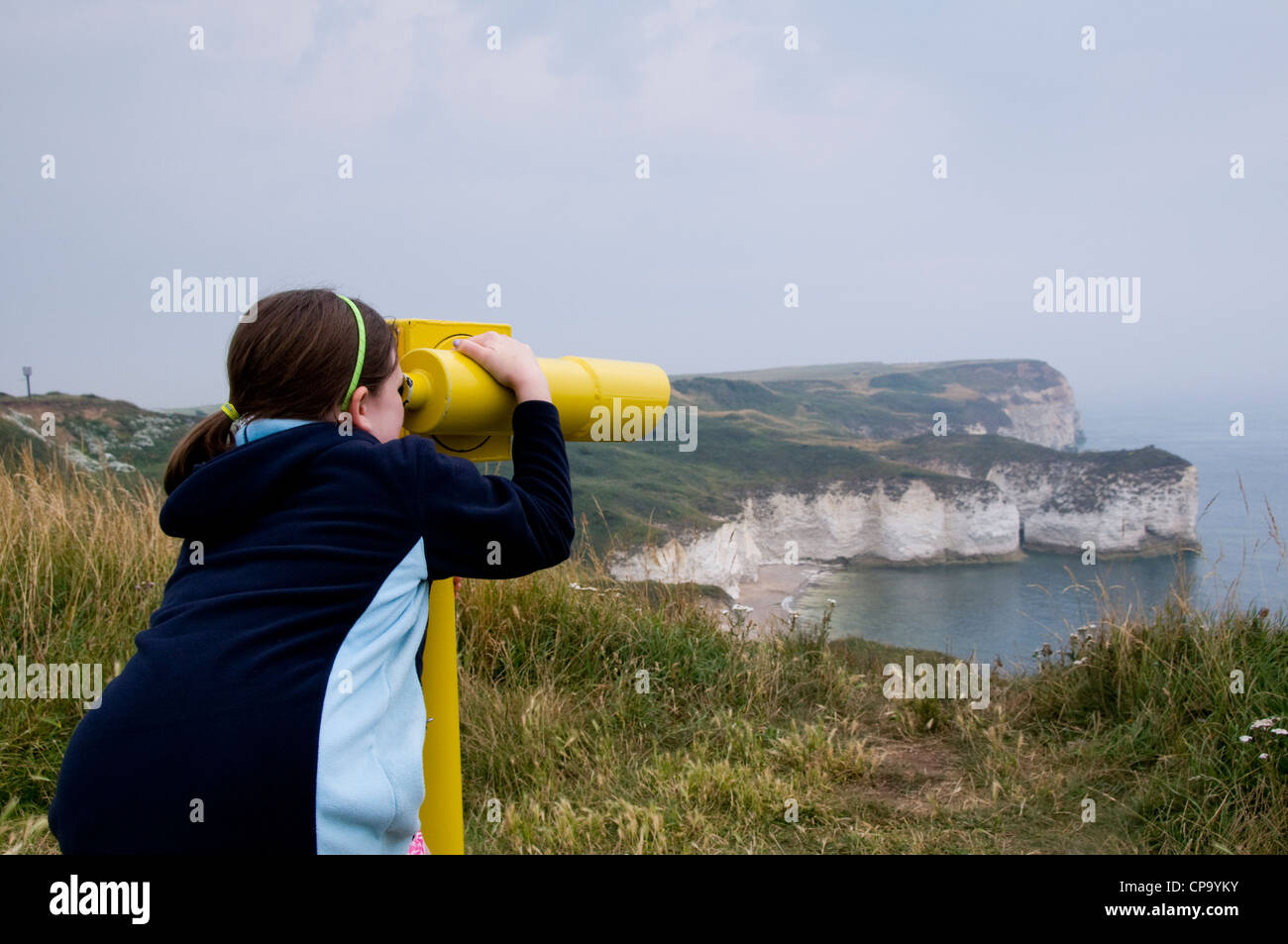 Une jeune fille à la recherche à travers un télescope vers Flamborough Head. Banque D'Images