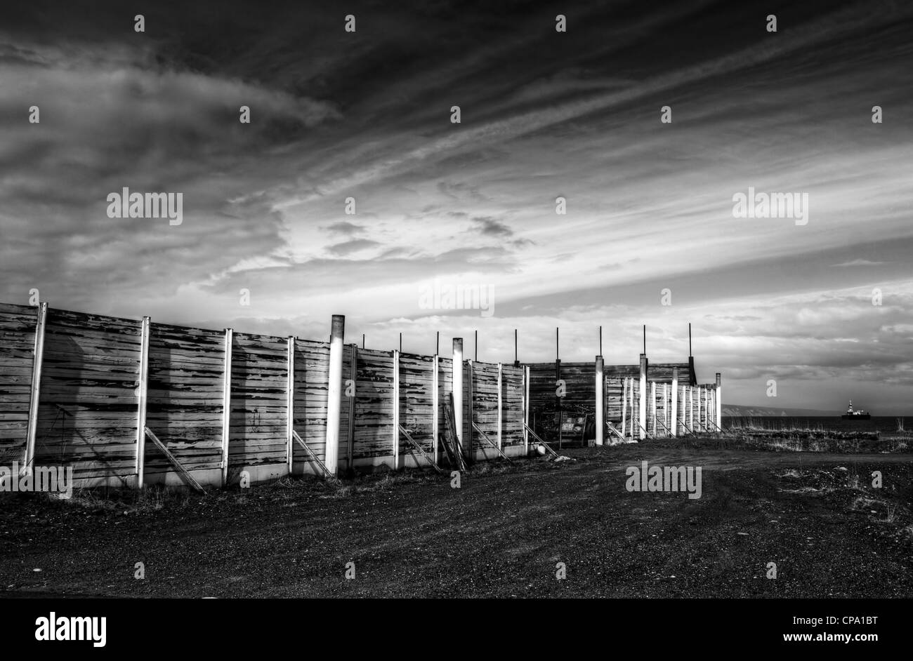 Vieille clôture dans un chantier industriel près du port en noir et blanc avec des nuages. Banque D'Images