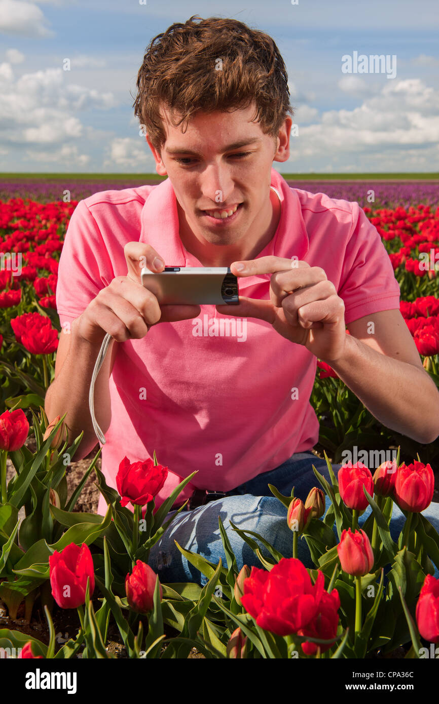 Jeune homme prend des photos dans le champ avec des tulipes en Hollande Banque D'Images