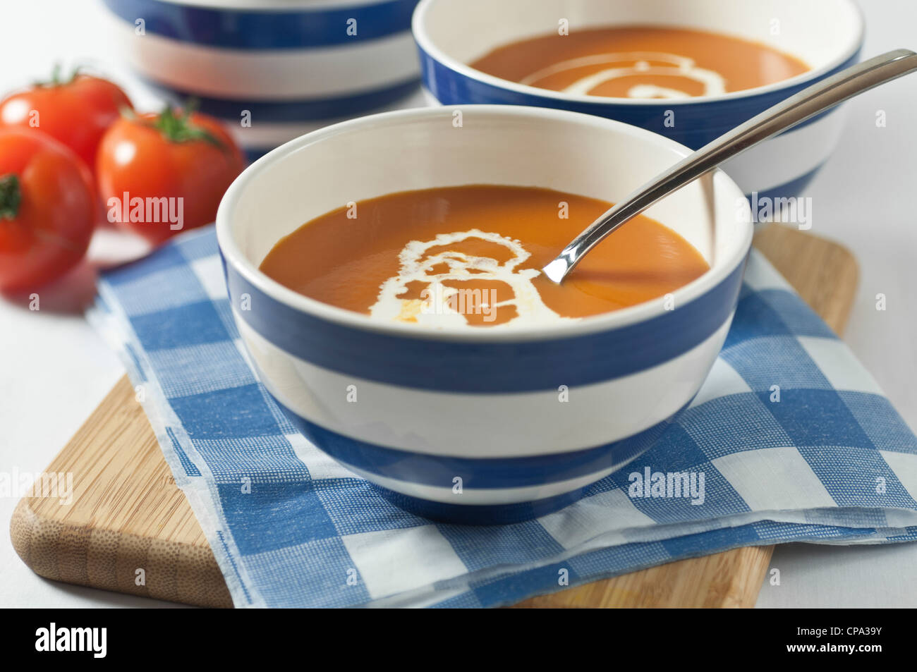 Soupe de tomate dans des bols rayé bleu et blanc Banque D'Images