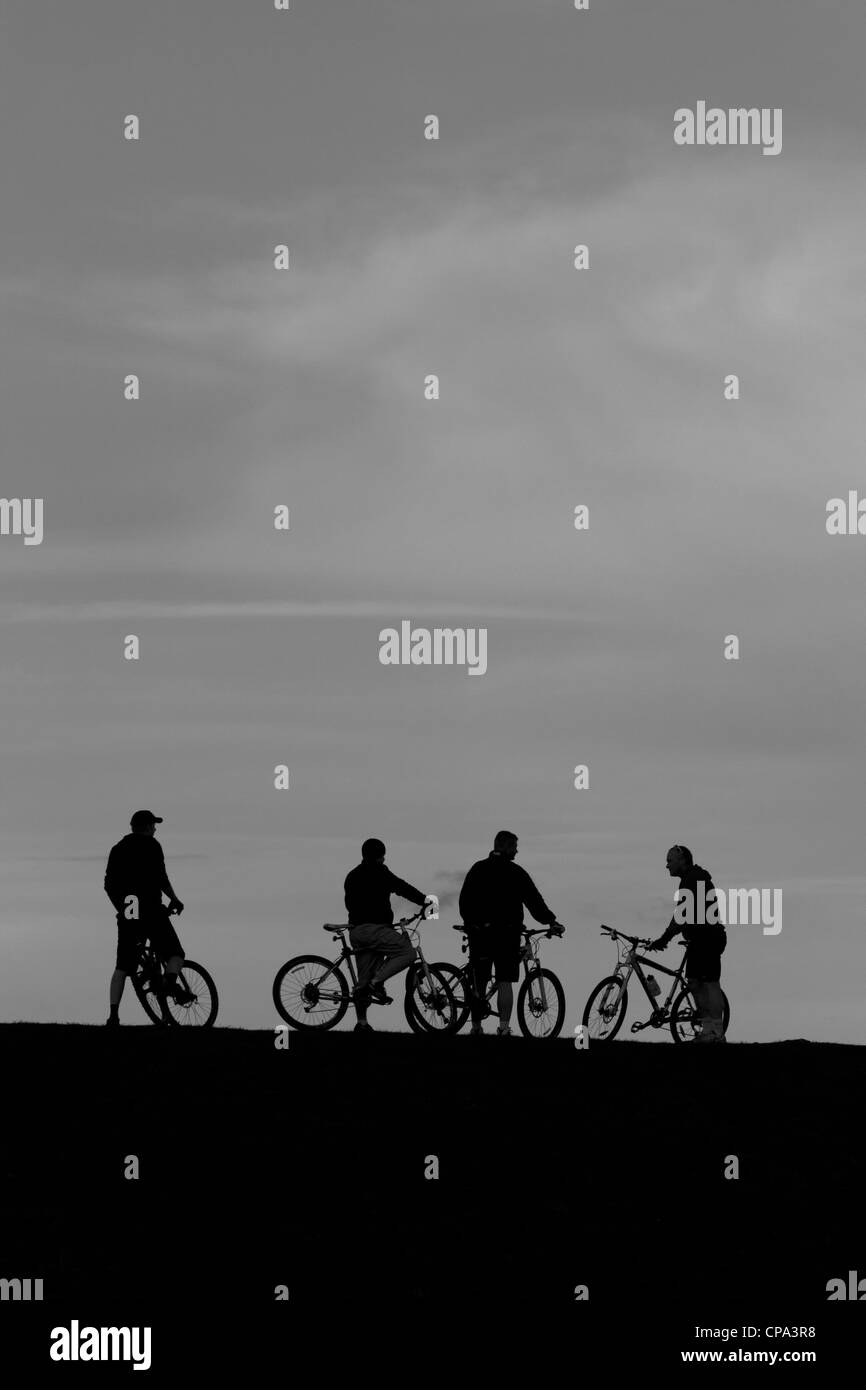 Groupe de mountain bikers on hillside at Dusk, England, UK Banque D'Images