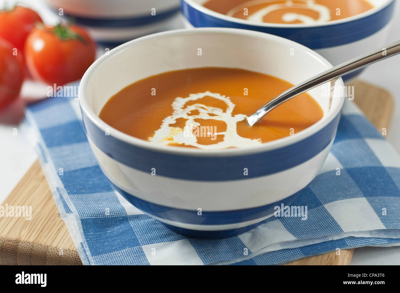 Soupe de tomate dans des bols rayé bleu et blanc Banque D'Images