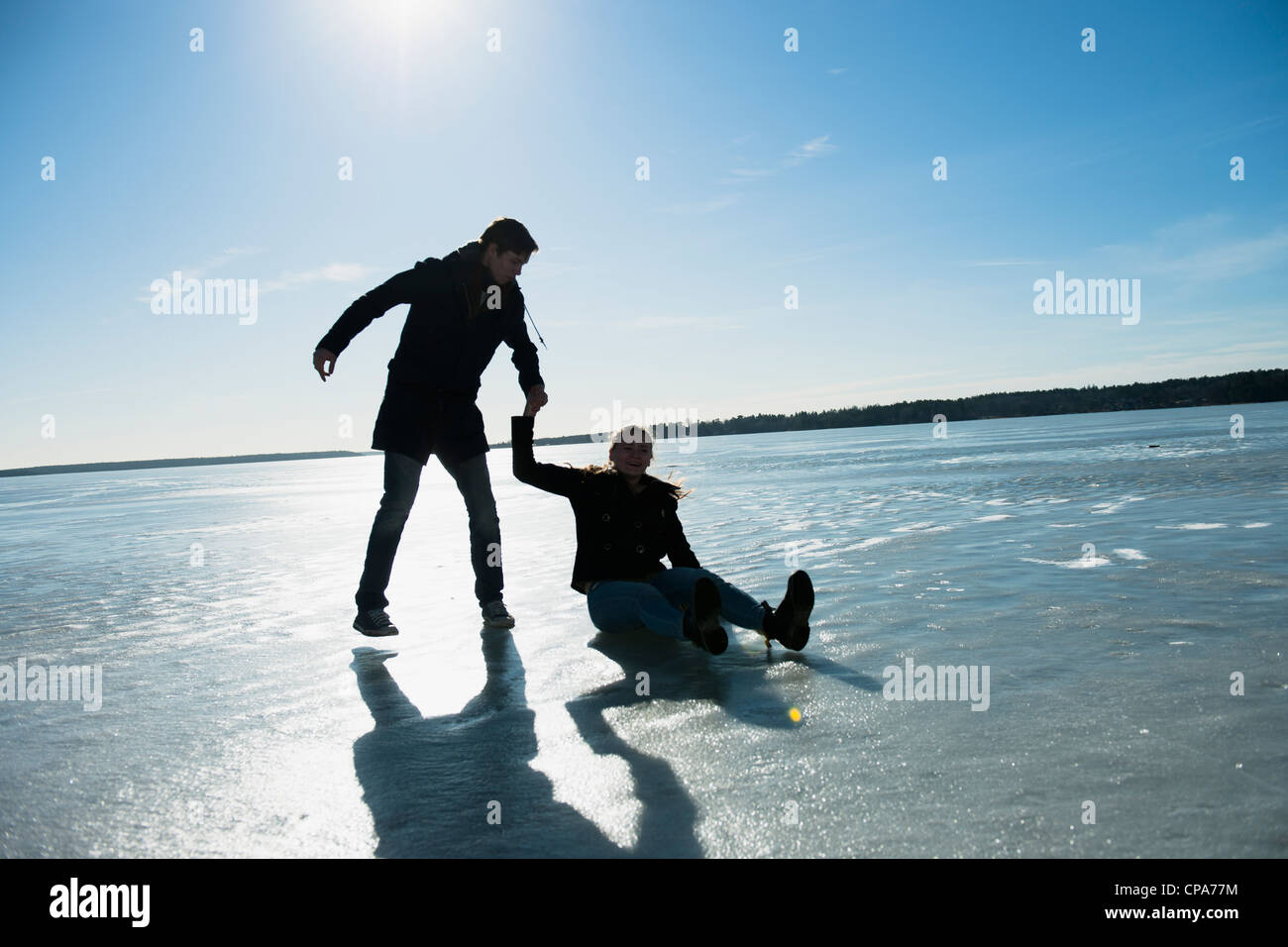 Jeune couple jouant sur la glace dans un lac gelé Banque D'Images