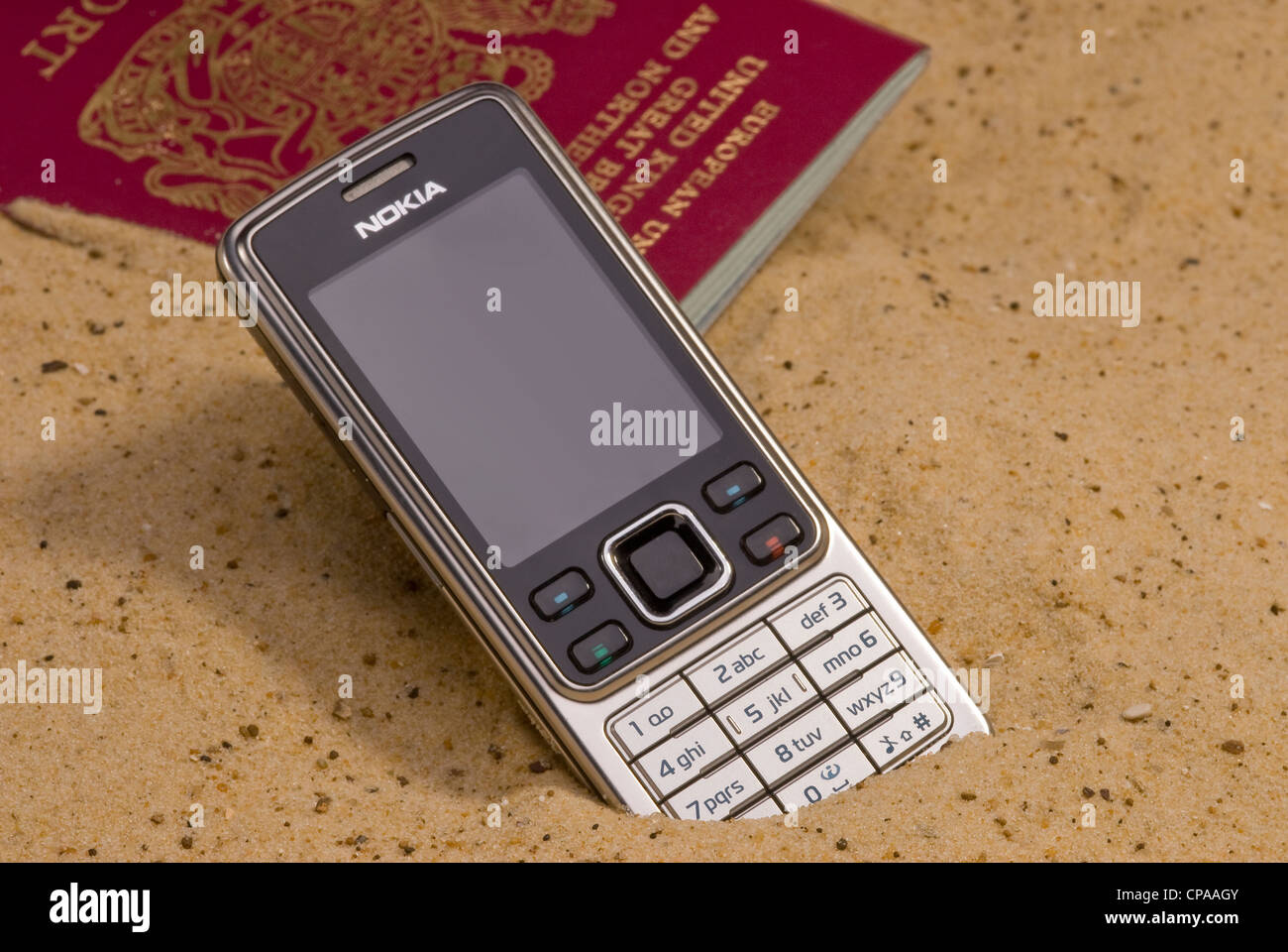 Passeport perdu et pose de téléphone mobile dans le sable. Banque D'Images