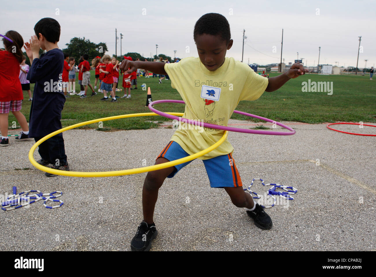 L'école primaire multi-ethnique age enfants le hula-hoop lors d'activités physiques au cours de la journée scolaire Banque D'Images