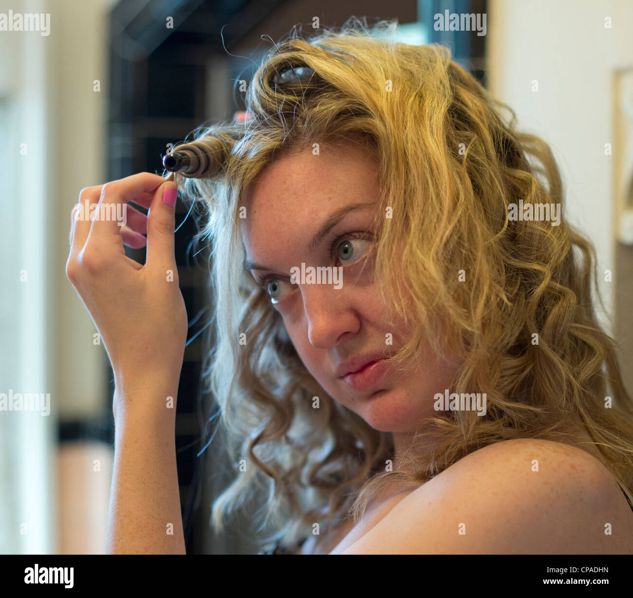 Mariel, 24 Ouest, utilise un fer à friser ses cheveux. Banque D'Images