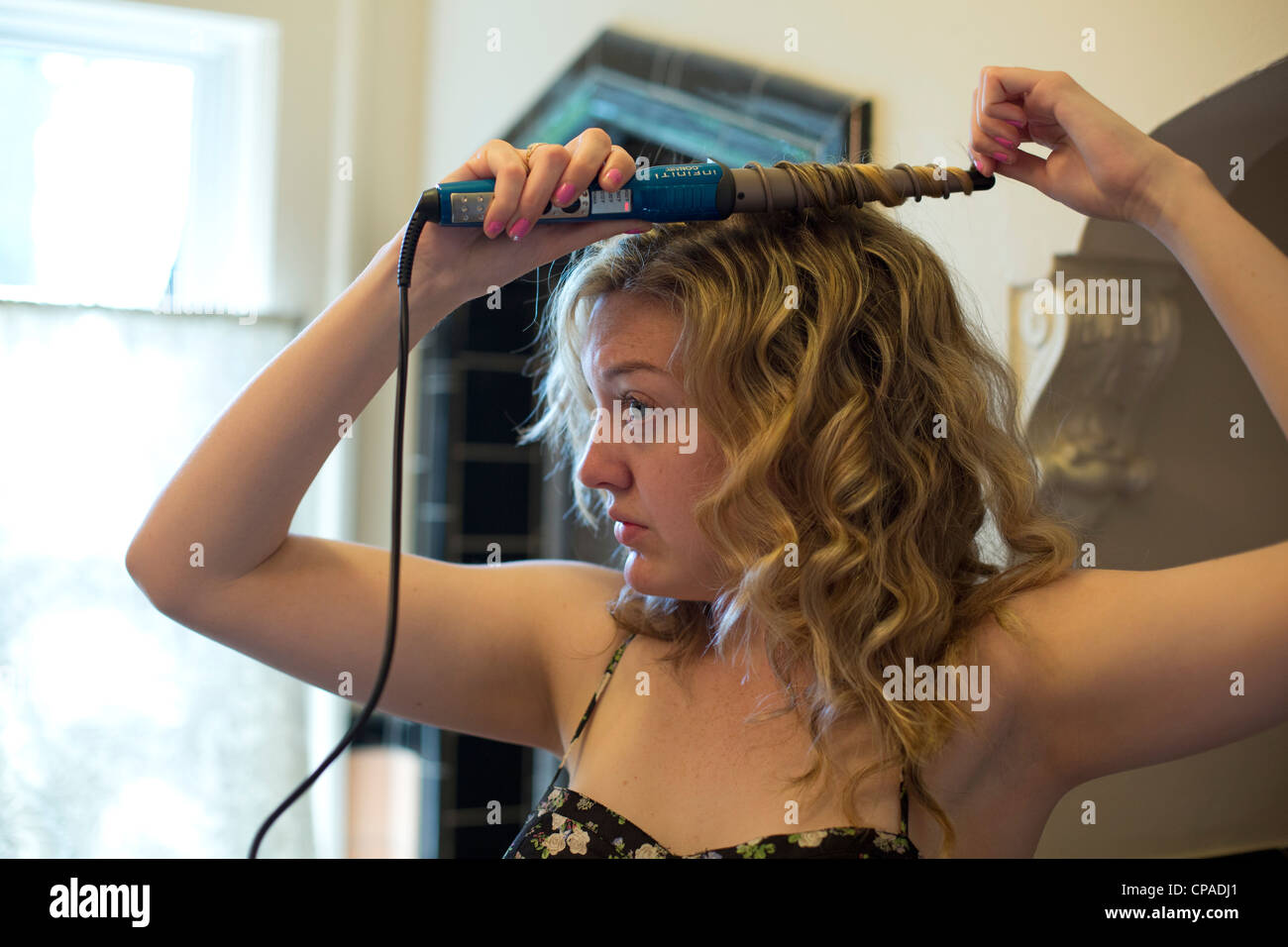 Mariel, 24 Ouest, utilise un fer à friser ses cheveux. Banque D'Images