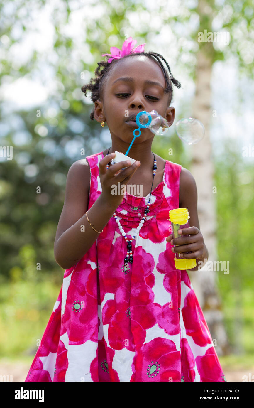 Portrait of a cute little girl blowing afro-américains des bulles de savon Banque D'Images
