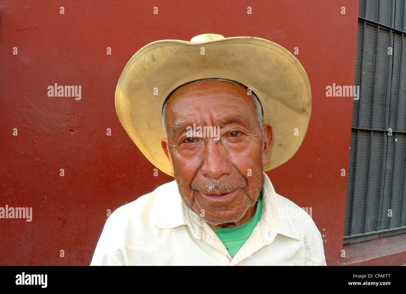 Guatemala Antigua smiling man with cowboy hat sitting par colorful wall scène de rue pavées site de l'Unesco Banque D'Images
