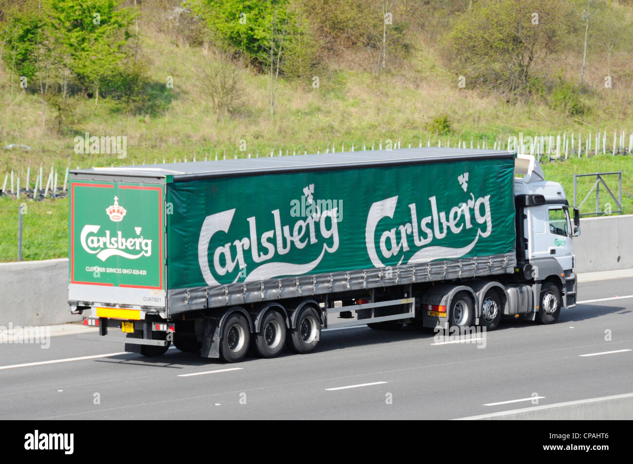 Le brasseur danois Carlsberg supply chain soft verso rideau articulé et remorque camion poids lourds de livraison camion conduisant le long de l'autoroute M25 Angleterre Essex UK Banque D'Images