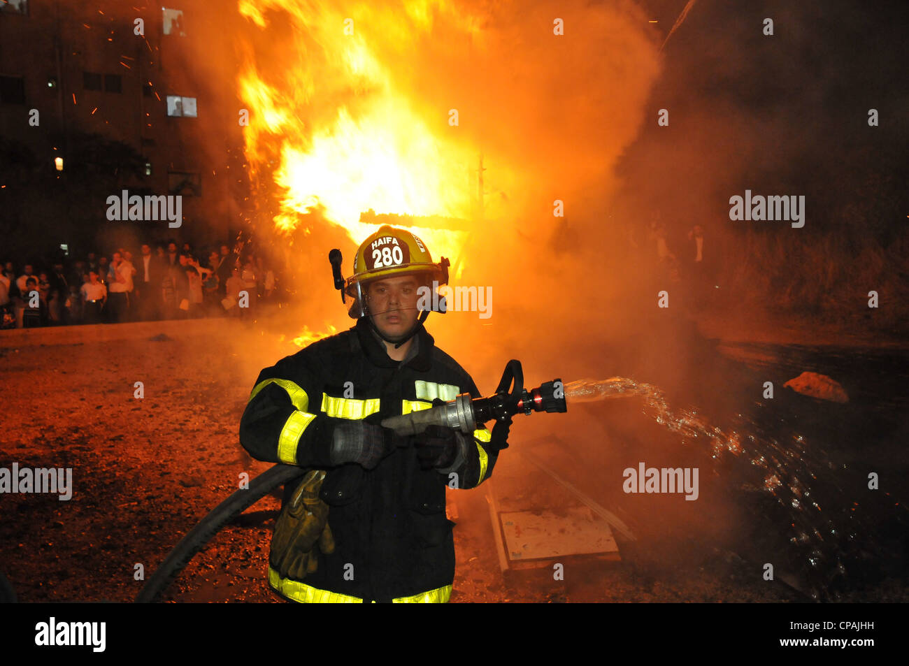 Un pompier éteint un incendie qui était hors de contrôle au cours de la célébration de la fête juive de Lag BaOmer à Haïfa. Banque D'Images