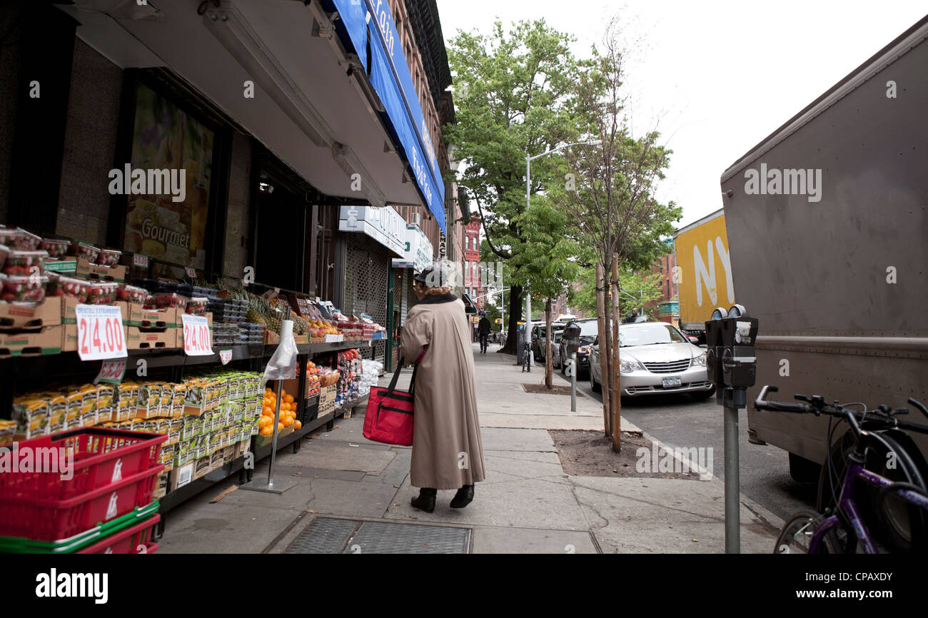 Une femme s'arrête à l'œil des fruits dans un marché à Brooklyn, New York. Banque D'Images