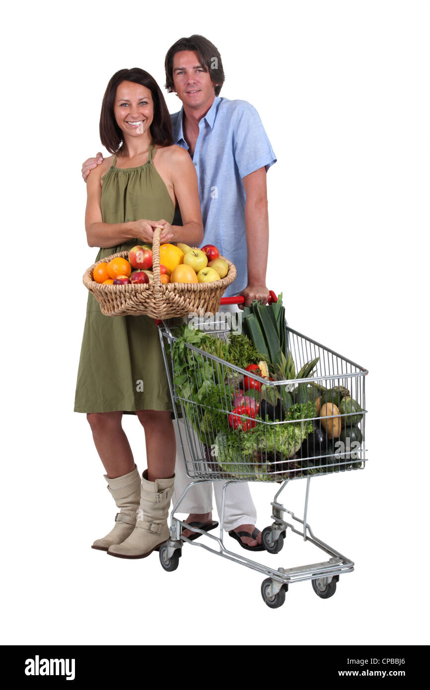 Couple avec un panier et chariot rempli de produits frais Banque D'Images