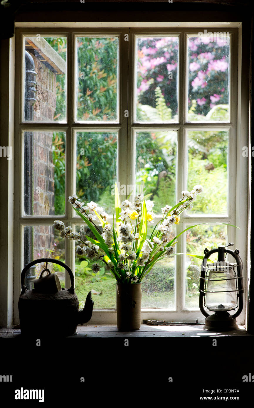 Vase de fleurs et d'une vieille lampe à huile dans la fenêtre de l'office de chefs jardiniers. Jardins perdus de Heligan, Cornwall, Angleterre Banque D'Images