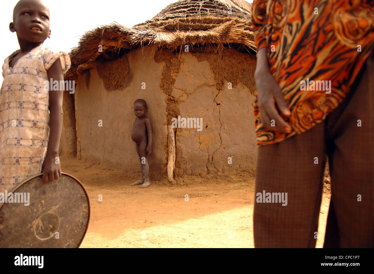 Un enfant mal nourri, devant une hutte de terre dans Liethnhom, Soudan. Août 2005. Banque D'Images