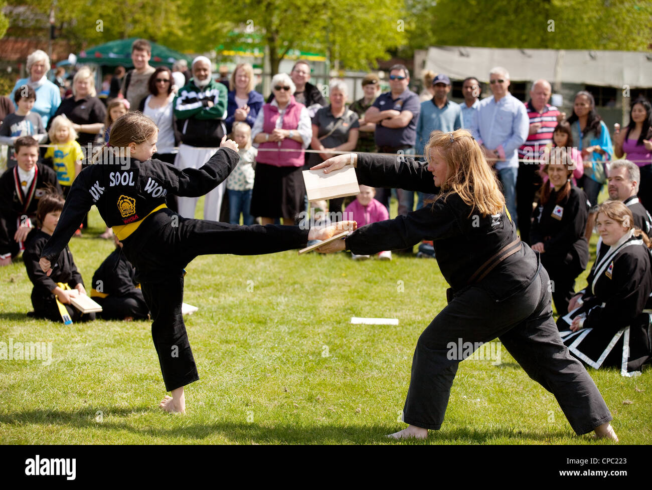 Une jeune fille de casser un morceau de bois avec un high kick faisant Kuk Sool Won, arts martiaux coréens, UK Banque D'Images