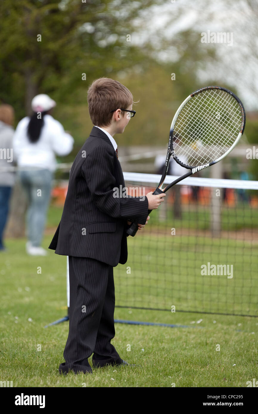 Plutôt comique vu de jeune garçon en costume et cravate en jouant au tennis, sports Newmarket Suffolk festival UK Banque D'Images