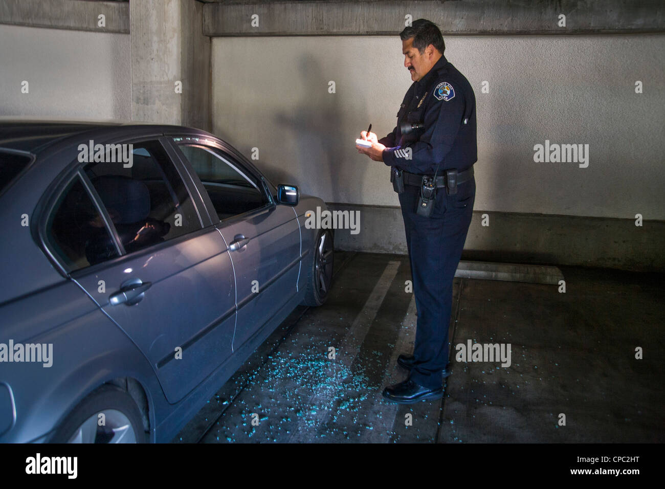 A Santa Ana, CA, agent de police hispaniques enquête sur une voiture qui a été cambriolé et volés dans un garage de stationnement de la ville. Banque D'Images