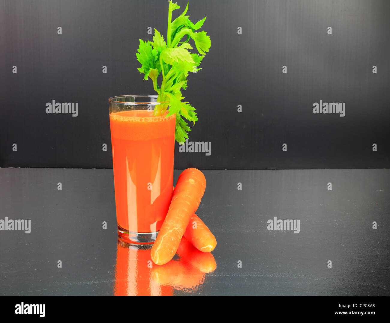 Jus de carottes avec le céleri dans un verre sur un banc en acier inoxydable haut Banque D'Images