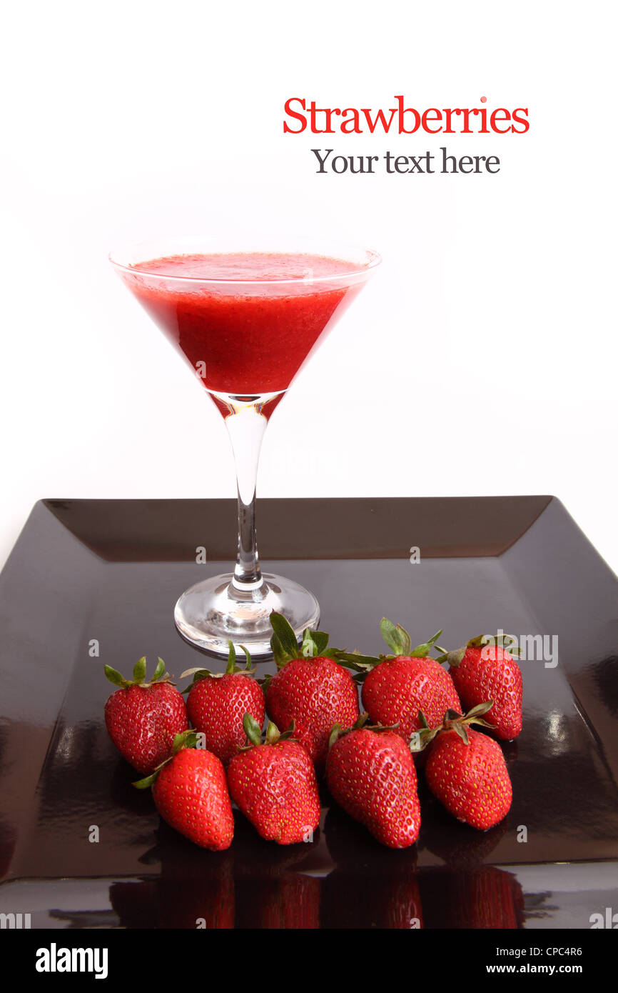 Jus de fraises dans un verre à cocktail avec un plat de fraises fraîches sur noir isolated on white Banque D'Images
