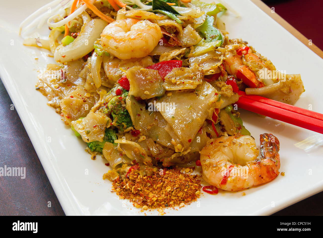Pad Thaï Kee Mao nouilles de riz aux crevettes et légumes et sur le côté de la poudre de chili épicé Banque D'Images