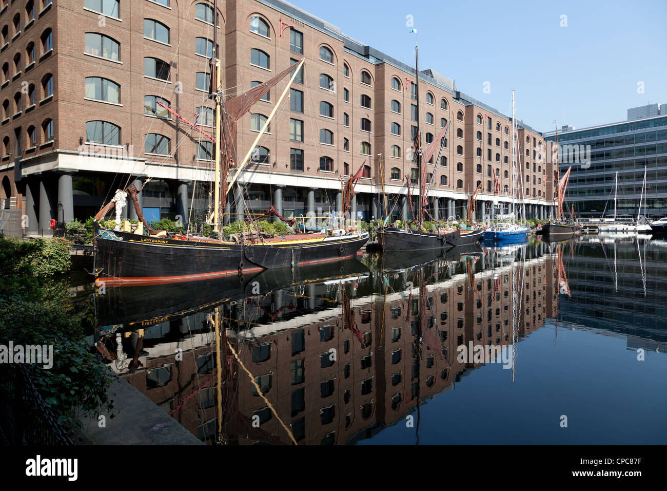 Vieux bateau à barges et les bâtiments reflètent dans l'eau de St Katharine Docks marina, East London Banque D'Images