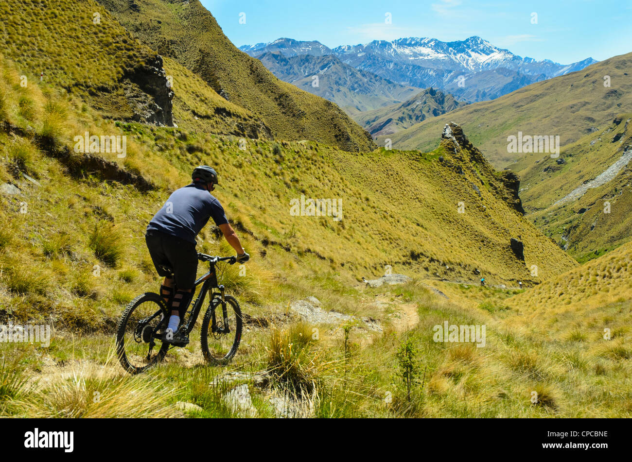 Les vététistes descendant le pack piste, Skippers Canyon, près de Queenstown, avec Mt Aurum sur l'horizon, Nouvelle-Zélande Banque D'Images