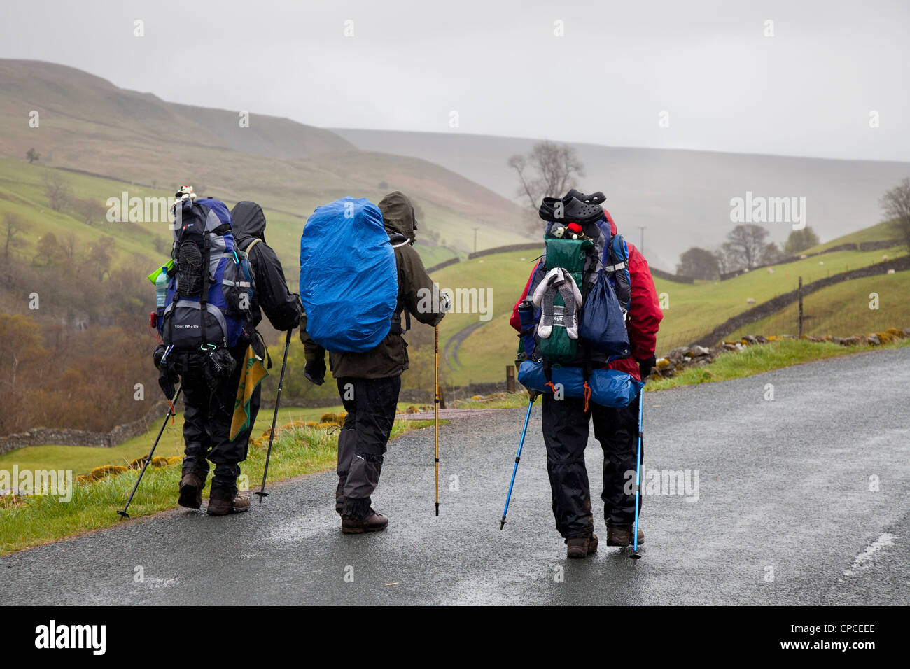 Trois hommes en randonnée; marcheurs d'un océan à l'autre à Swaledale. Homme sur la route de Keld à Gunnerside, et Reeth, North Yorkshire National Park, Royaume-Uni Banque D'Images