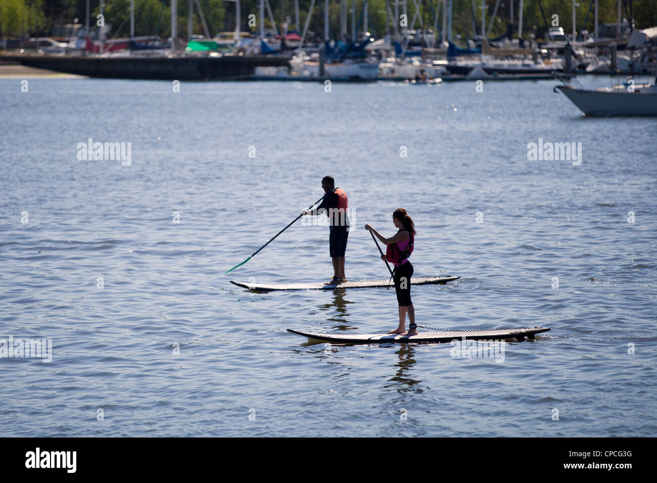 Un couple paddleboarding sur l'eau calme Banque D'Images
