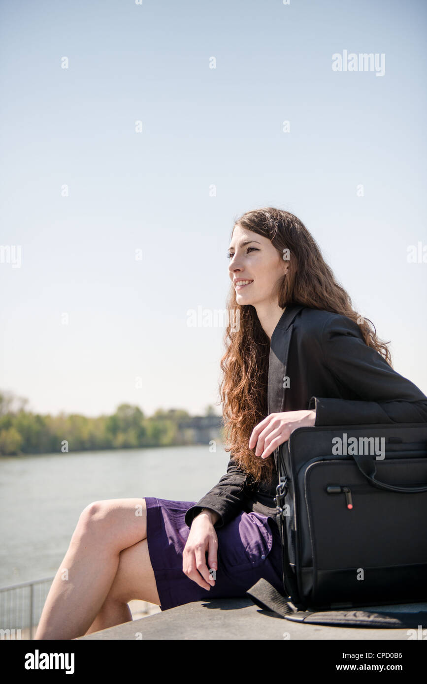 Young smiling business woman portrait avec ordinateur portable sac - assis dans la nature Banque D'Images