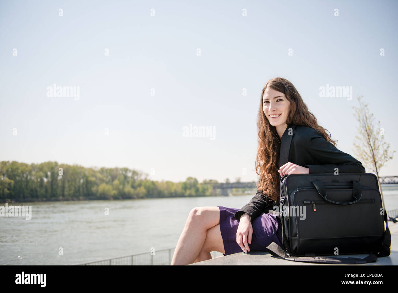 Young smiling business woman portrait avec ordinateur portable sac - assis dans la nature Banque D'Images