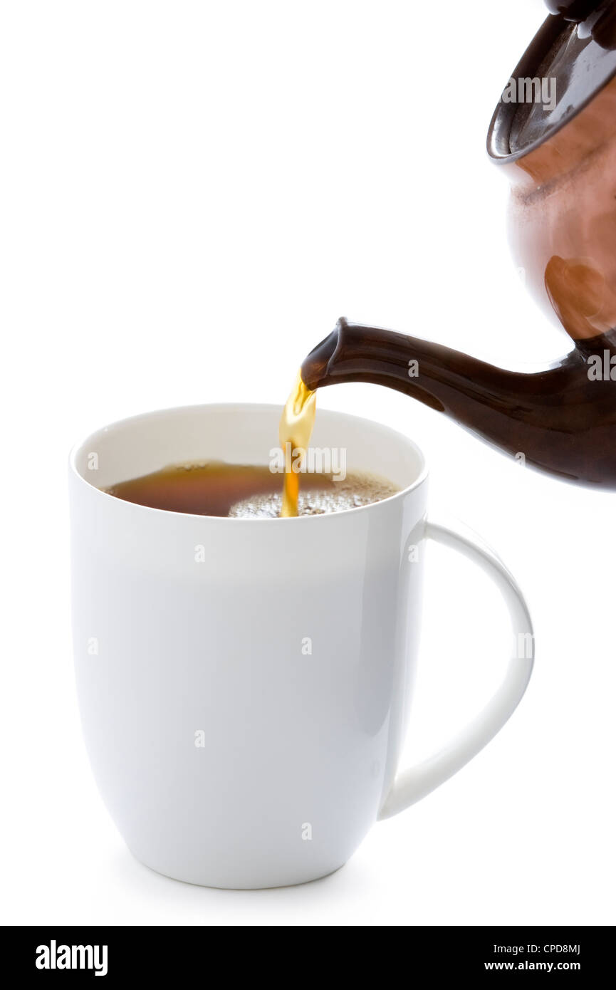 Verser un pot de thé le thé dans une tasse blanche Banque D'Images