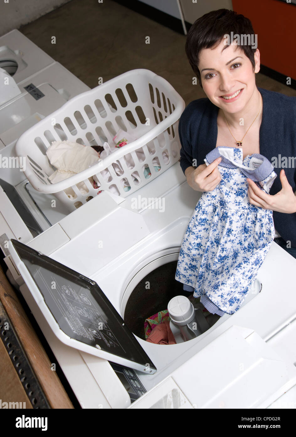 Une femme tire vêtements de la rondelle au niveau de la laverie Banque D'Images
