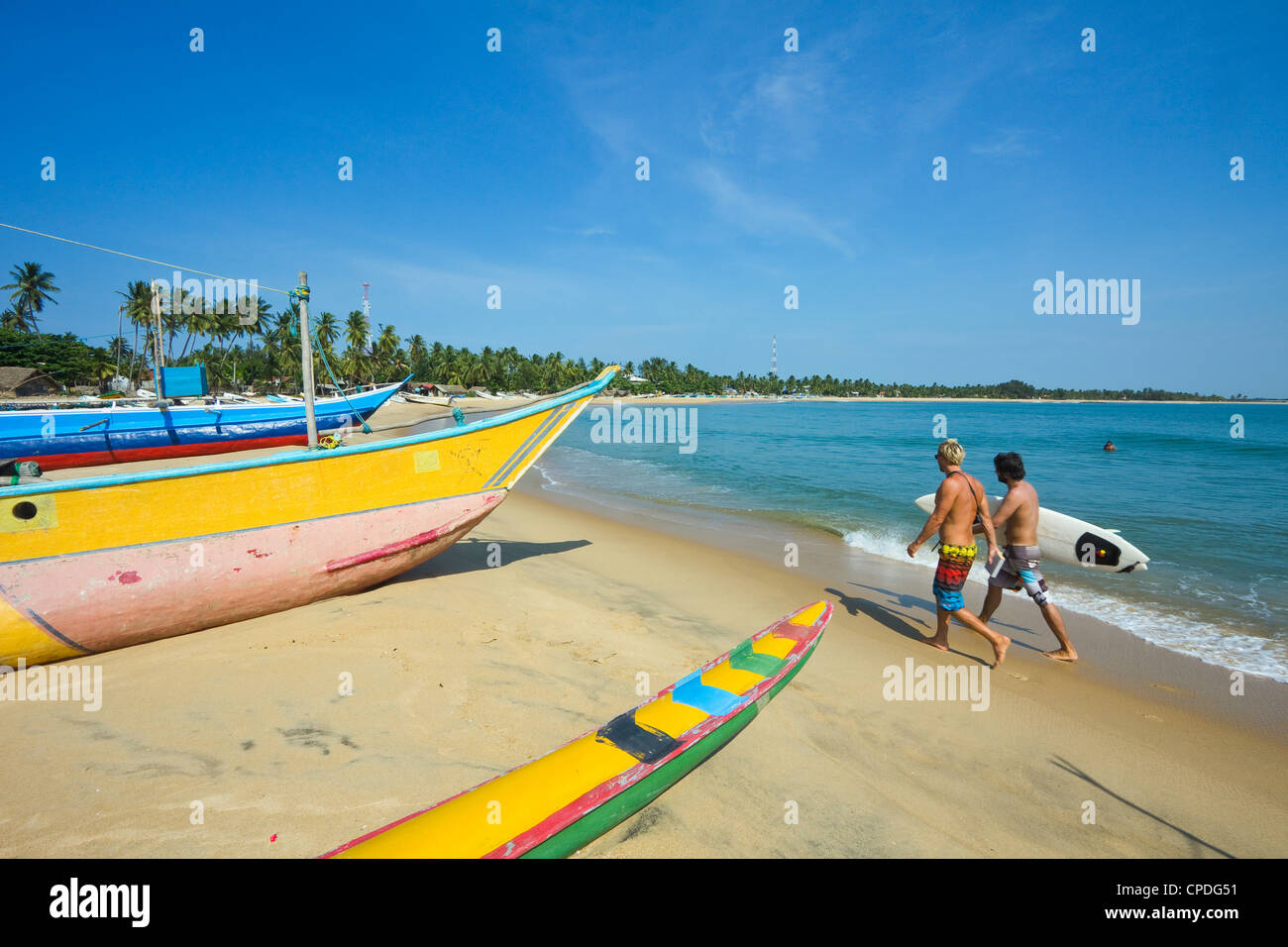 Les surfers et les bateaux de pêche sur la plage de surf populaire, durement touchée par le tsunami de 2004, d'Arugam Bay, Province Orientale, au Sri Lanka Banque D'Images