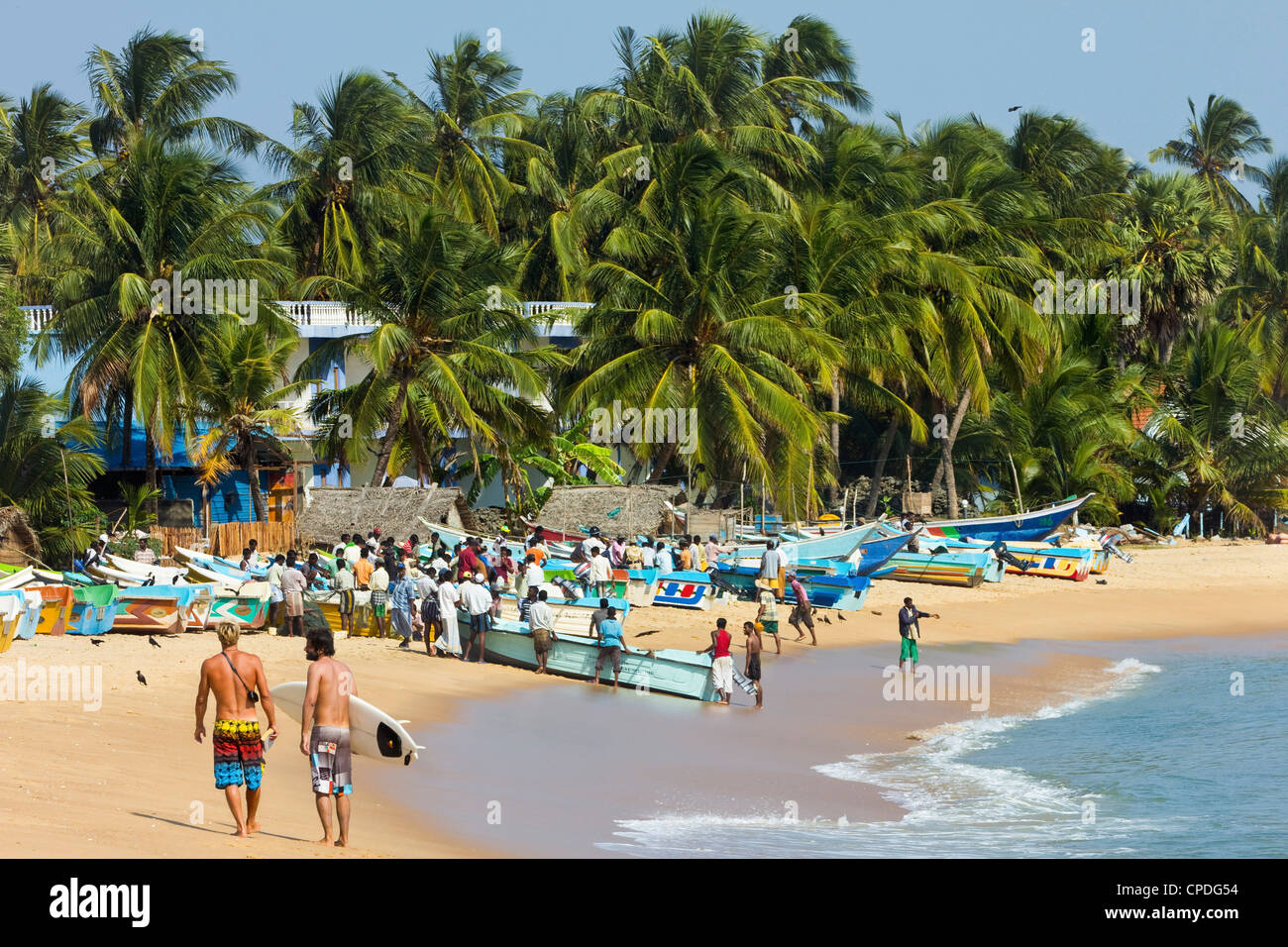 Les touristes se promener tandis que les pêcheurs locaux, les travaux sur cette plage de surf populaire, d'Arugam Bay, province de l'Est, Asie, Sri Lanka Banque D'Images